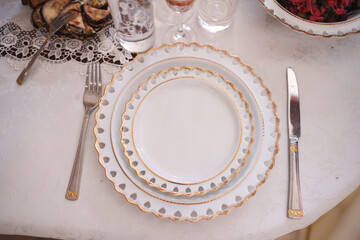 The table is served with classic white and gold dishes. Table setting for a banquet.