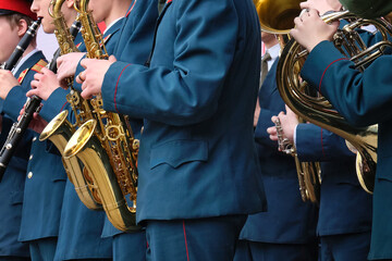A children's brass band in military uniform plays at a festival in a city park.