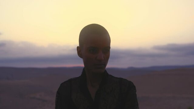 Model with shaved head posing in front of the camera in desert
