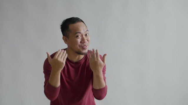 Attractive Asian Man Greet Warmth Welcoming and Inviting to Come With Hand Isolated on Gray Background