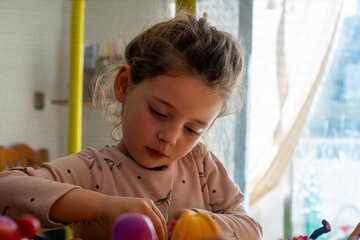 Thoughts at Play: The thoughtful expression of a girl engaged in her activities at home with...
