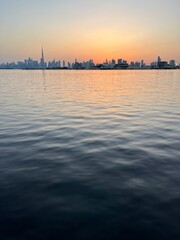 Naklejka premium city river at the sunset time, down town silhouette at the background, orange sky, water reflection 