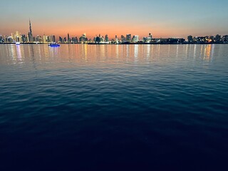 city river at the sunset time, down town silhouette at the background, orange sky, water reflection 