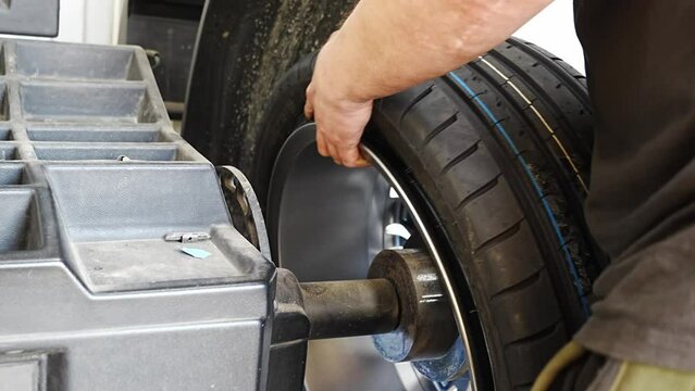 Installing the wheel on the balancing machine. Tire service in a car repair shop. without a face.