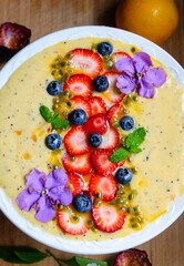 Passion fruit smoothie bowl with  strawberry and blueberry topping 