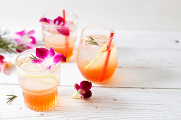 Glass of iced summer soda with lemon and pink orchid flower.