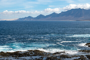 View on difficult to access golden sandy long Cofete beach hidden behind mountain range on Fuerteventura, Canary islands, Spain