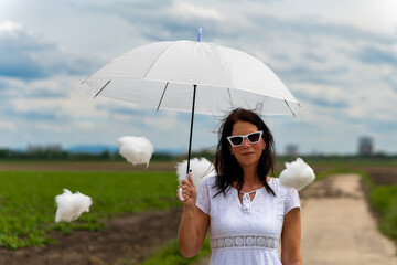 woman is holding a white umbrella and surrounded by cotton clouds