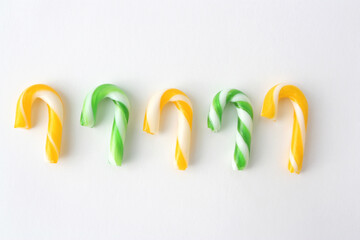 Christmas candies in yellow and green on a white background. New Year concept.Candies in the form of Santa's staff.