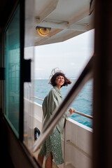 Obraz premium girl stands on the deck of a cruise ship. The girl is traveling. A young beautiful brunette travels on a yacht.