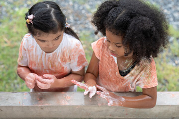 Little girls washing hands with soap at an outdoor faucet after activity outdoor painting...