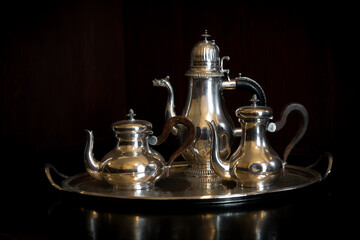 old antique polished silver coffee set against dark black wooden background for aristocracy and old...
