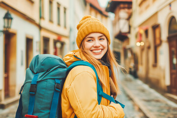 Smiling traveler girl in street of old town in European city. Young backpacker female tourist enjoy solo travel. Vacation, holiday, trip, exchange program, digital nomads lifestyle