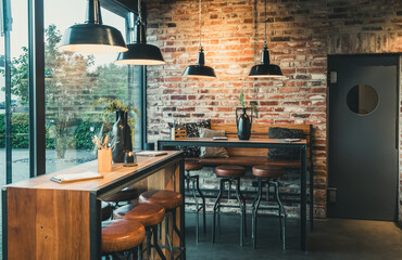 Seating area with bar tables and bar chairs in a modern cafe, industrial style with stone wall,...