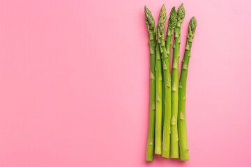 there is a bunch of green raw young asparagus on a pink background. healthy eating. spring vegetables. healthy food. vegan