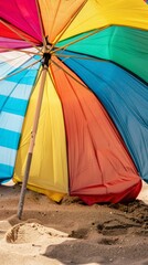 Close-up of a colorful beach umbrella casting a cool patch of shade on the hot sand