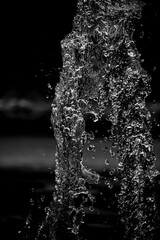 Gouttelettes en suspension d'un jet d'eau d'une fontaine - Arrière plan sombre noir et blanc