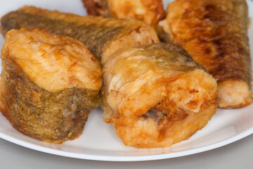 Fried hake pieces on dish close-up in selective focus
