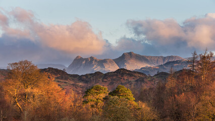 Beautiful Spring landscape image in Lake District looking towards Langdale Pikes during colorful sunset