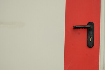 Black door handle against a white background with a wide red stripe