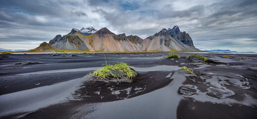 Landscape in panorama format of the famous mountain range Vestrahorn with a beach of black volcanic...