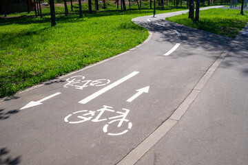 Winding cycleway with pictograms and directional guidance in summer park