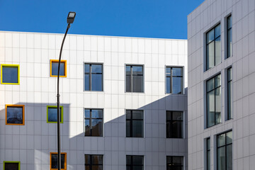 A fragment of an office building with white walls and windows of different sizes. Finishing with composite panels of the ventilated facade.