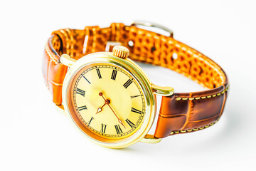 A classic wristwatch with a brown leather strap and a gold face with Roman numerals, displaying the current time, resting on a pristine white background.