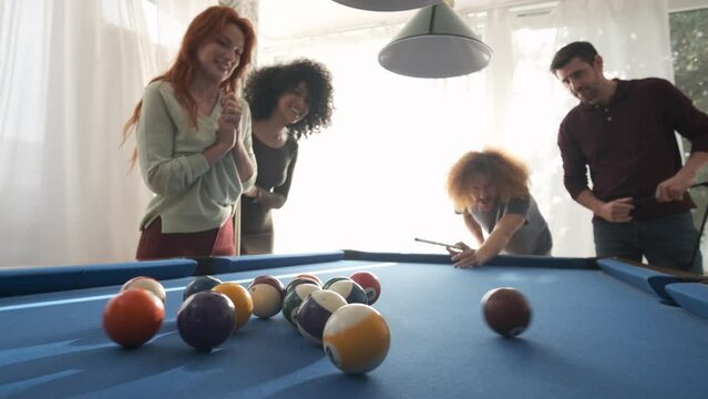 Man playing pool with friends in game room at home