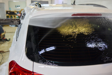 Fototapeta premium Foam covers car in garage tires, wheels, lights, hood, automotive design
