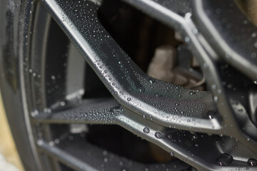 Closeup of automotive tire with water drops on rim and spokes