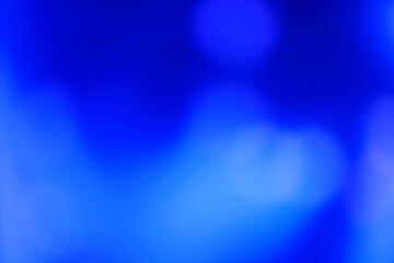 Abstract image with soft undefined shapes of blue color and blurry lights like those of a music concert stage.