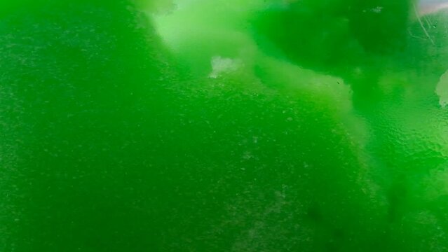 Drops of condensation on the green ice cream tank. Ice cold sorbet machine mixing fruit juice. Freezing slush spinning around, summer treat.