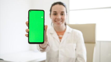 Happy female doctor showing chromakey on smartphone in clinic