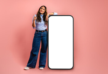 Model woman smiling with thumbs up, leaning on a giant cell phone