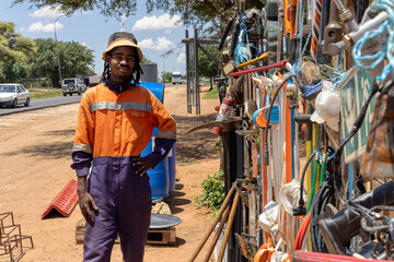 african street vendor selling hardware on the side of the road, wearing orange workwear and...