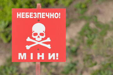 A bright red sign with a skull and an inscription warns of mine danger