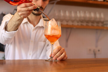 Waiter preparing a fresh orange cocktail at a bar table