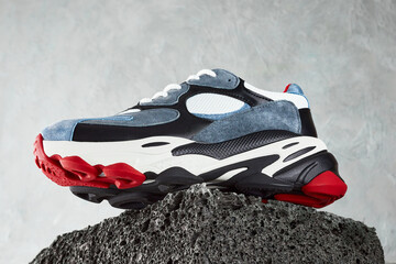 Sneakers on dark gray concrete background. Texture of the old dark stone or broken brick. The concept of shoes for the outdoor and off-road.