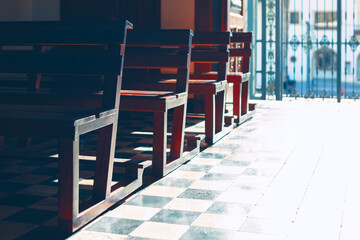 Chairs in a row on the floor inside of the church. Wooden benches for praying 