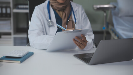 A professional and focused Asian female doctor in scrubs is working and reading medical research on...