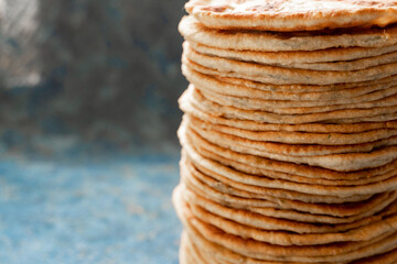 Flatbread lavash, chapati, naan, heap of tortilla on a blue background Homemade flatbread stacked.