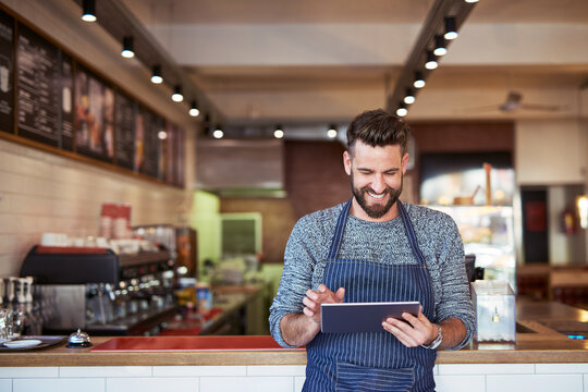 Businessman, restaurant or cafe on tablet with smile for small business owner, social media update or sales promotion. Happy, male person or waiter on technology for coffee shop news or online blog