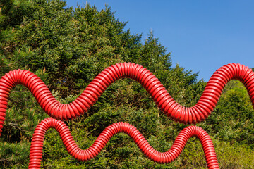 森の中にあった波状の赤いパイプのオブジェ