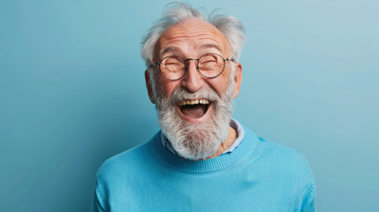 Elderly man with glasses and a beard laughing joyfully against a pale blue background, wearing a light blue sweater, radiating happiness and warmth.