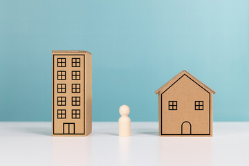 Housing, mortgage, real estate investment and residential building concept. Wooden figurines deciding between a house or a condo in investment residential