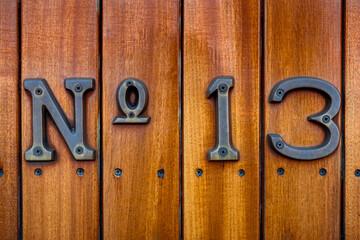 Close-up of a weathered No 13 sign affixed to the wooden planked exterior of a train wagon,...