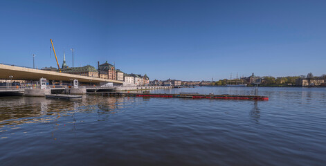 Fototapeta premium The new sluice gate at the old town Gamla Stan, the yellow steel bridge Guldbron, a sunny spring day in Stockholm