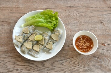 Vietnamese steamed rice dumpling stuffed chop pork and topping slice sausage with fresh green lettuce salad on plate dipping sweet chili sauce dressing crispy fried shallot in cup