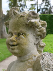 Gesicht einer barocken Steinstatue einer Putte (Engel) im Schloßgarten Veitshöchheim (Bayern, Deutschland)